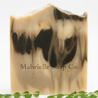 Close-up macro of Mabrielle Moringa Grove Goat Milk Soap showing cream and dark green moringa swirl artisan texture