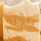 Close-up of Mabrielle Soap Co. embossed logo and cream orange swirl texture on handmade soap bar